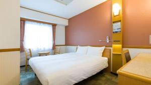 米泽市Toyoko Inn Yonezawa Ekimae的一间酒店客房,配有一张白色的床和一张书桌