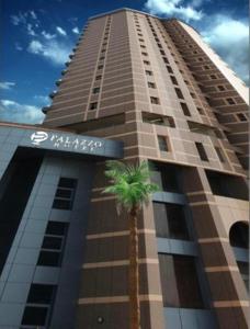 a tall building with a palm tree in front of it at Palazzo hotel in Kuwait