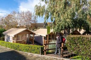 Una donna è in piedi di fronte a una casa di legno di hu Roma Camping In Town a Roma