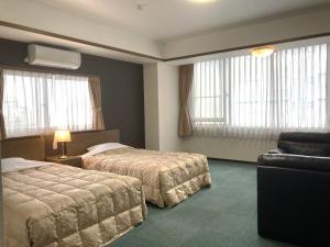 a hotel room with two beds and a couch at Itoen Hotel in Ito