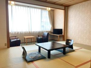 a living room with a coffee table and chairs at Itoen Hotel in Ito