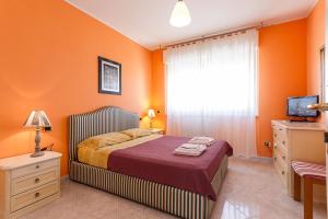 a bedroom with orange walls and a bed and a television at B&B Mareya in Cagliari