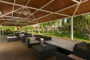 zadaszone patio z kanapami, stołami i drzewami w obiekcie Iberostar Waves Punta Cana w Punta Cana