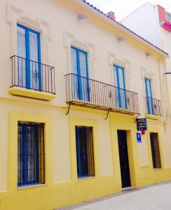 un edificio amarillo con ventanas y balcones azules en Hotel Conde de Cárdenas, en Córdoba