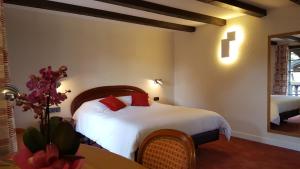 a bedroom with a bed with white sheets and red pillows at Hotel Restaurant Père Benoît in Entzheim