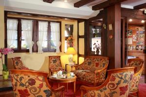 a living room with chairs and a table and windows at Hotel Restaurant Père Benoît in Entzheim