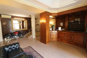 a living room with a leather couch and a kitchen at Hotel Dei Tigli in Angera