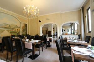 a dining room with tables and chairs and a chandelier at Hotel Dei Tigli in Angera