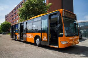 einem orangenen Bus, der an der Straßenseite parkt in der Unterkunft Bastion Hotel Amsterdam Airport in Hoofddorp