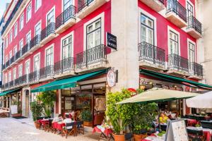 a pink building with tables and umbrellas in front of it at Rossio Garden Hotel in Lisbon