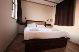 a bedroom with a bed with white sheets and a window at The Market Courtyard - Suites Hotel in Jerusalem