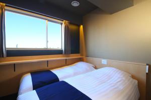 Hotel Wing International Select Asakusa Komagata في طوكيو: غرفة نوم صغيرة بها سرير ونافذة