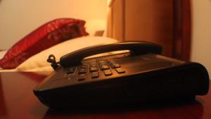 um telefone preto sentado numa mesa ao lado de uma cama em Hotel Residence Flamani em Lomé