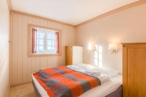 a bedroom with a bed with a striped blanket at Ilsetra Hotell in Hafjell