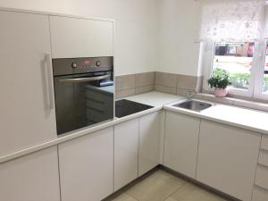 una cocina con armarios blancos y fregadero en Apartments Cindra, en Karlovac