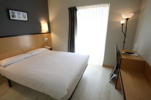 een slaapkamer met een groot wit bed en een raam bij Hotel Alda Entrearcos in Burgos