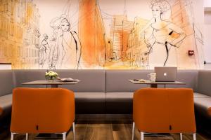 un restaurant avec un canapé et deux tables avec des chaises orange dans l'établissement 43 Station Hotel, à Milan