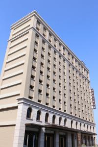 een hoog wit gebouw met een blauwe lucht op de achtergrond bij Fushin Hotel - Tainan in Tainan