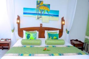 a bedroom with a bed with two green pillows at Voyager Beach Resort in Mombasa