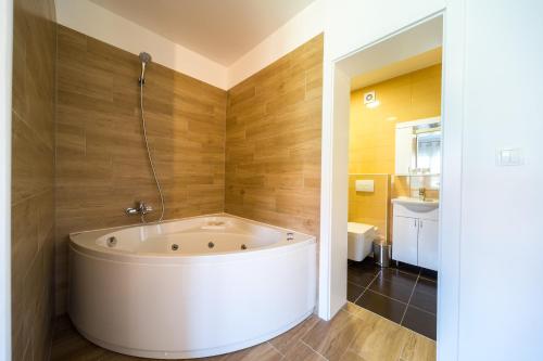 a large white tub in a bathroom with wooden walls at Villa Gradski Vrt in Osijek