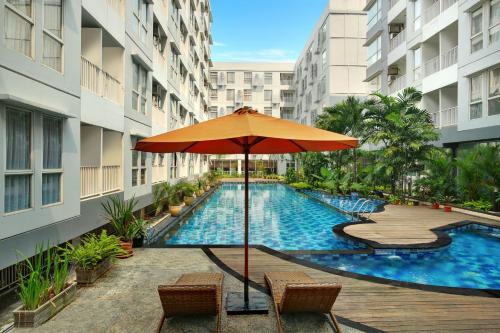 an umbrella and chairs next to a swimming pool at Kyriad Hotel Airport Jakarta in Tangerang