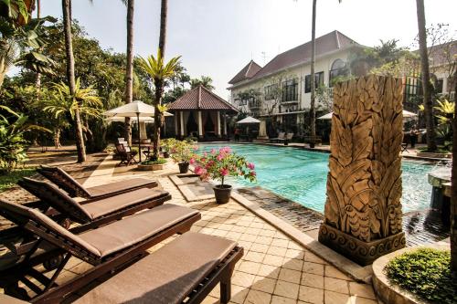 een zwembad met ligstoelen naast een resort bij Sarasvati Borobudur in Borobudur