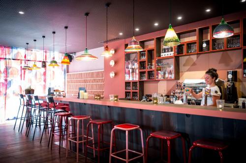 a woman standing behind a bar with red stools at BOMA easy living hotel in Strasbourg