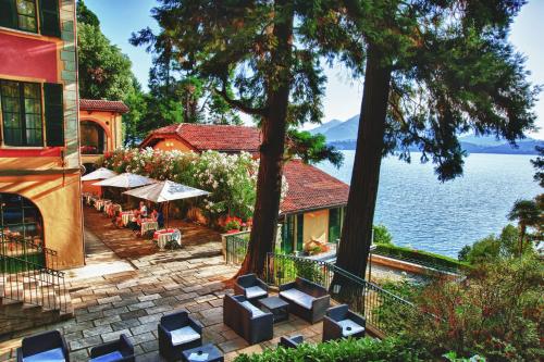 a patio with chairs and tables next to the water at Relais Casali della Cisterna in Belgirate