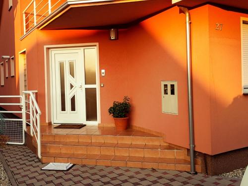 uma casa laranja com uma porta branca e um vaso de planta em Apartment Dominik em Osijek