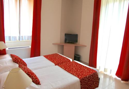 a bedroom with a bed with red curtains and a television at Santanna in Verbania