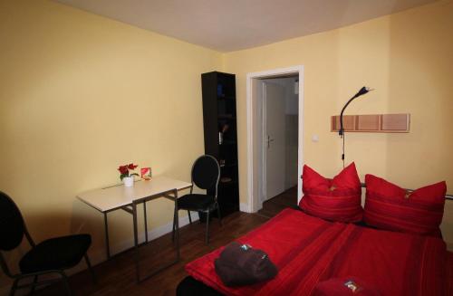 1 dormitorio con cama roja, mesa y sillas en Sleep in Hamburg St. Pauli, en Hamburgo