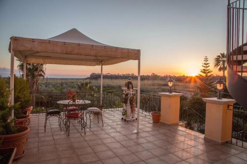 a patio with a table and chairs and the sunset at Palmed Hotel in Gizzeria