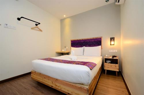 a bedroom with a large white bed with a purple headboard at Artisan Eco Hotel in Petaling Jaya