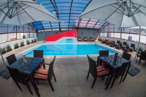 an indoor pool with tables and umbrellas at Hotel Riazor Aeropuerto in Mexico City