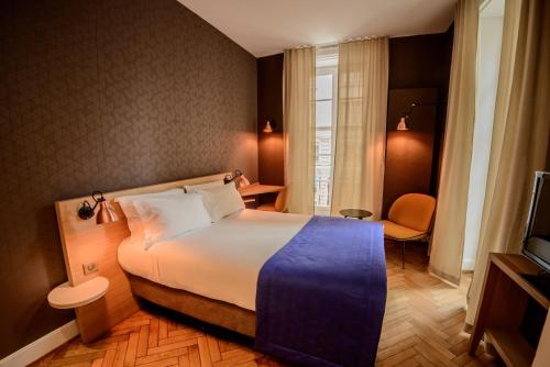 a hotel room with a bed and a television at HANNONG Hotel & Wine Bar in Strasbourg