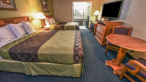 um quarto de hotel com duas camas e uma mesa e uma televisão em Chariot Inn Glendale - Pasadena em Glendale