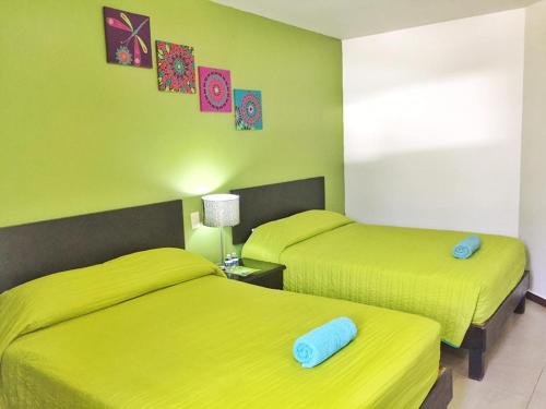 two beds in a room with lime green walls at Hotel Plazha in Tuxtla Gutiérrez