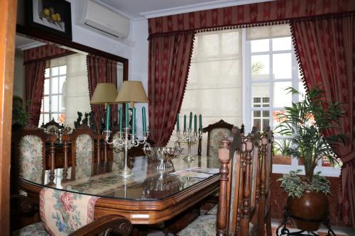 comedor con mesa de cristal y algunas ventanas en Boutique house LujoPobre, en Montilla