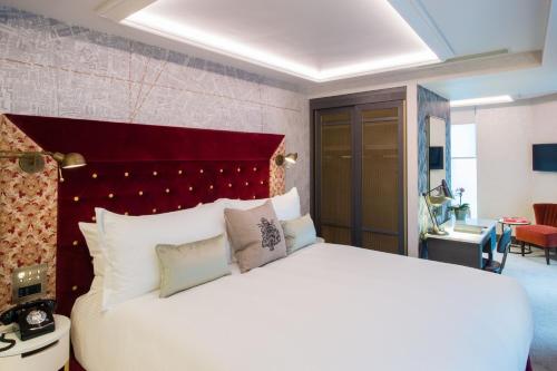 a bedroom with a large white bed with a red headboard at Vintry & Mercer Hotel - Small Luxury Hotels of the World in London