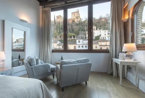 una camera da letto con un letto e due sedie e una grande finestra di Shine Albayzín a Granada