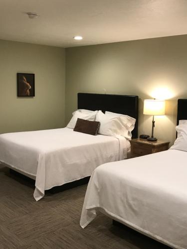 a hotel room with two beds with white sheets at Driftwood Lodge in Springdale