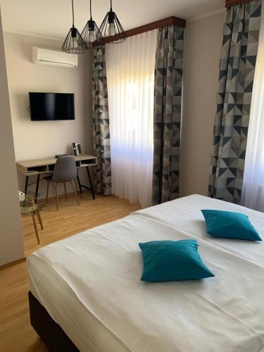 a bedroom with a large white bed with two blue pillows at Pansion Waldinger in Osijek