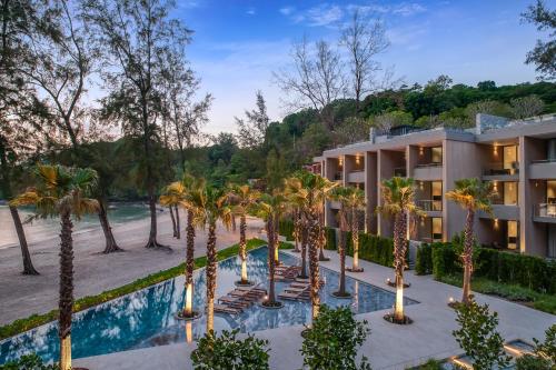 an apartment building with palm trees in front of a pool at Twinpalms MontAzure Phuket Resort in Kamala Beach