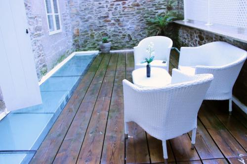 a patio with white chairs and a table with a plant at Hotel Montenegro Compostela in Santiago de Compostela