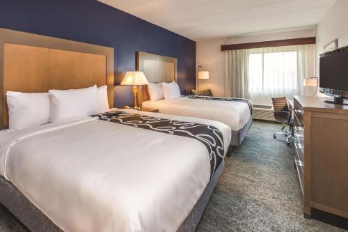 a hotel room with two beds and a television at La Quinta by Wyndham Philadelphia Airport in Essington