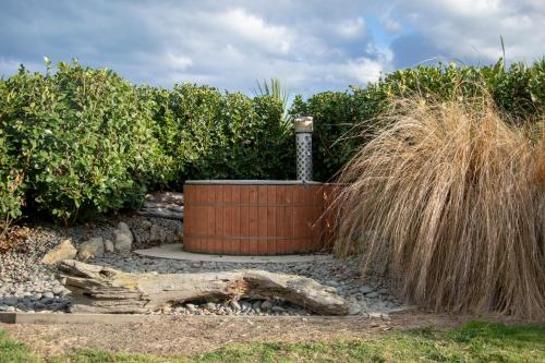 a hot tub in a garden with tall grass at Old Bones Lodge in Oamaru