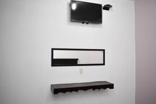 a flat screen tv hanging on a wall with a shelf at HOTEL LOS PINOS CENTRO in Tuxtla Gutiérrez