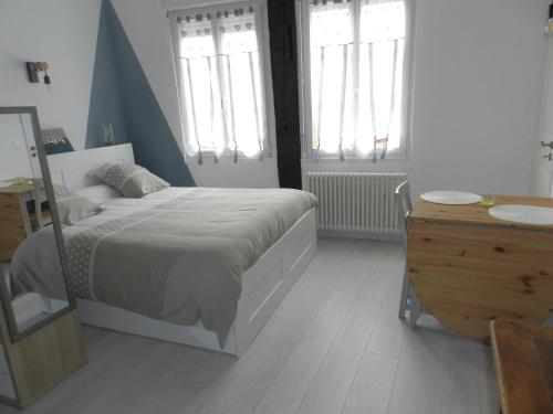 - une chambre avec un lit, une commode et des fenêtres dans l'établissement L IMPREVU, à Chartres