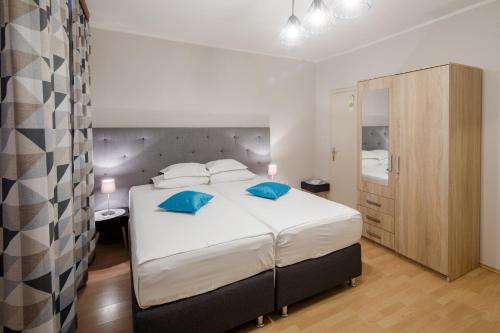 a bedroom with a large bed with blue pillows at Pansion Waldinger in Osijek