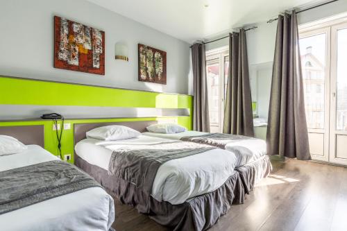 two beds in a room with green and white at Hotel Esplanade in Strasbourg